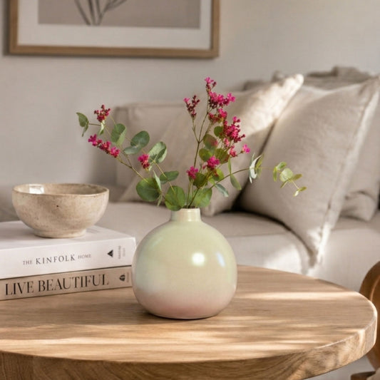 Luxury round ceramic flower vase in minimalist modern design held in hand against vibrant pink background for premium home décor and office styling.