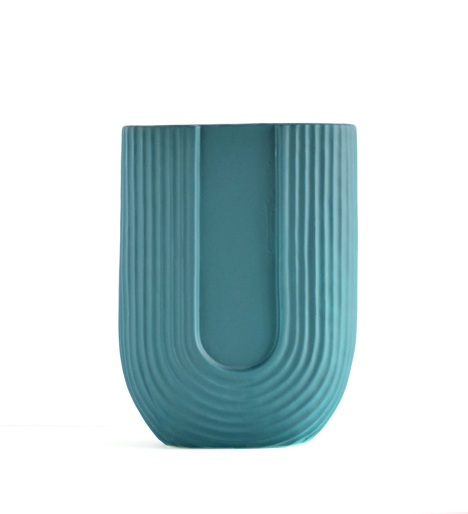 Modern dark green ribbed ceramic flower vase with yellow floral arrangement on minimal beige background