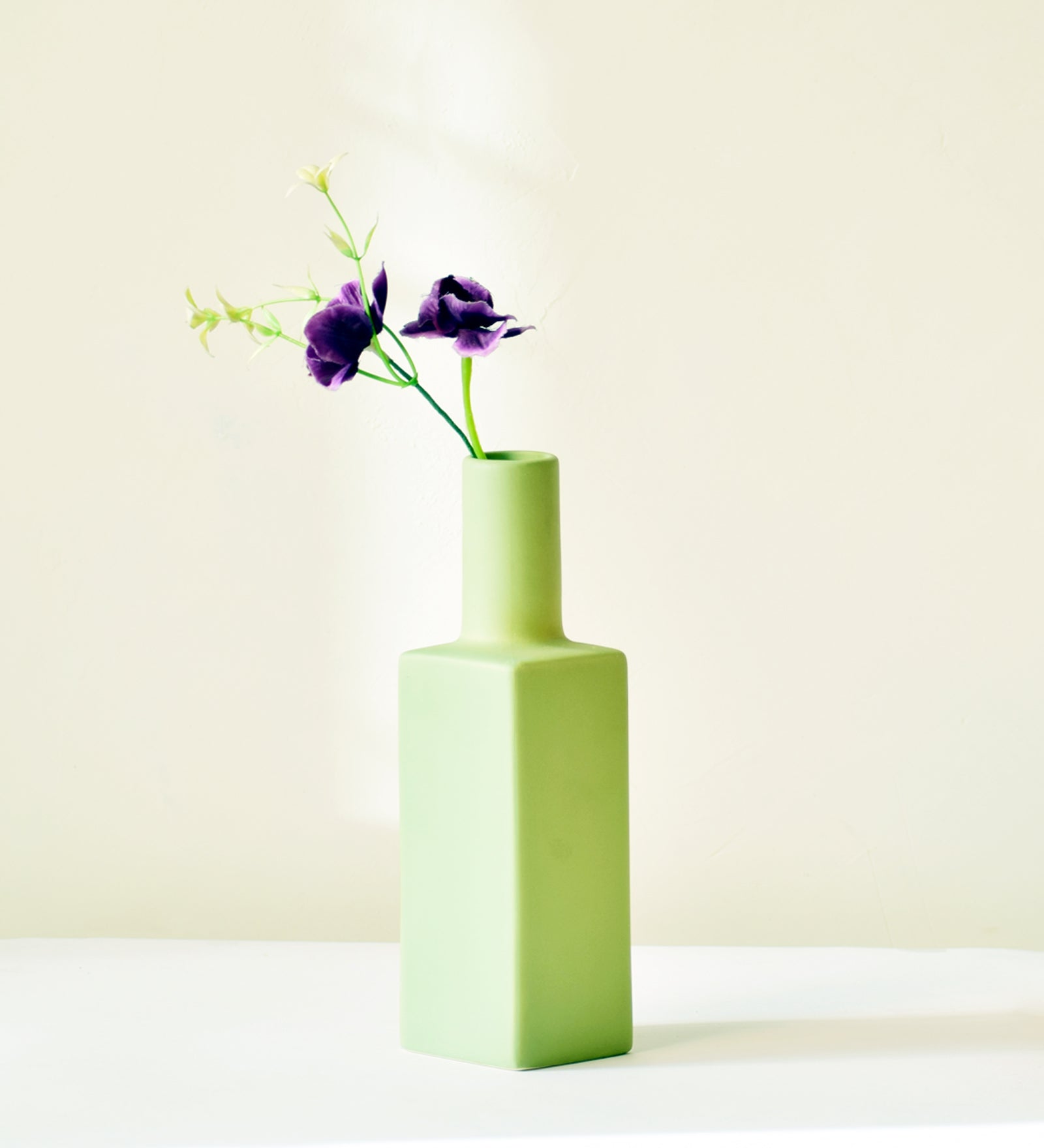 Luxury ceramic bottle-shaped vase with matte finish styled on a beige travertine console table in a modern Scandinavian-inspired interior with olive branches and minimalist décor.