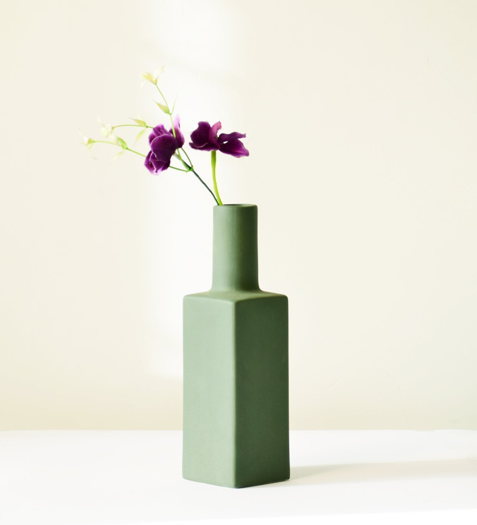 Luxury ceramic bottle-shaped vase with matte finish styled on a beige travertine console table in a modern Scandinavian-inspired interior with olive branches and minimalist décor.